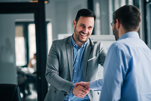 Portrait of cheerful young manager handshake with new employee.